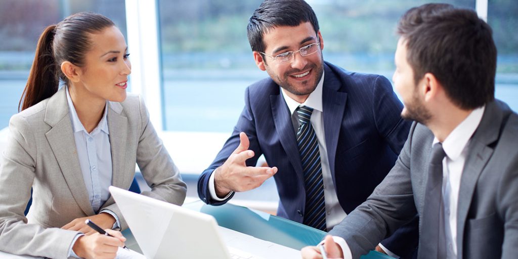 3 business men and woman sit around a table