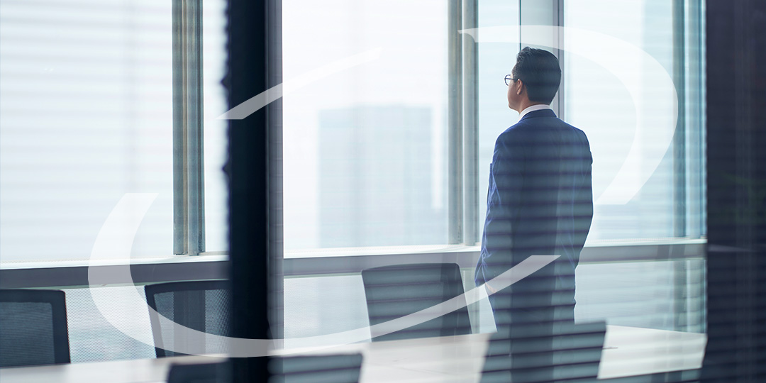 A business man staring out the window of his office building