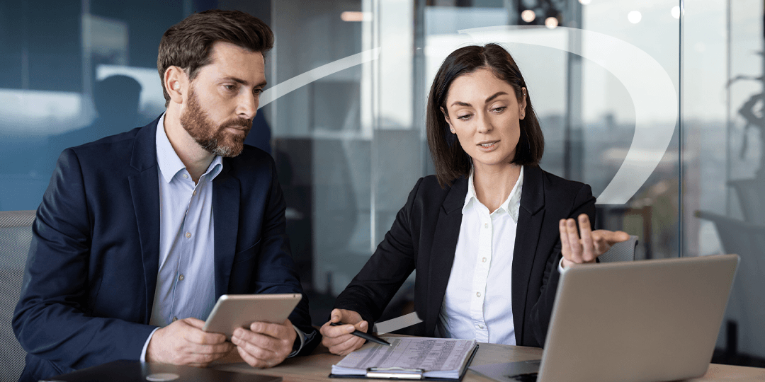 two businessmen sit discuss a spreadsheet