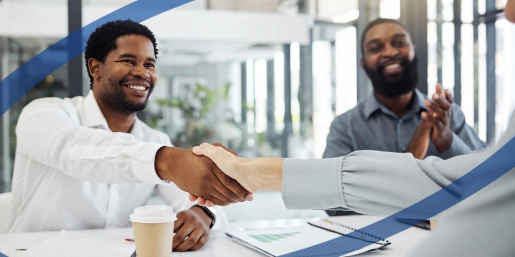 Two men shaking hands another man clapping in a business setting