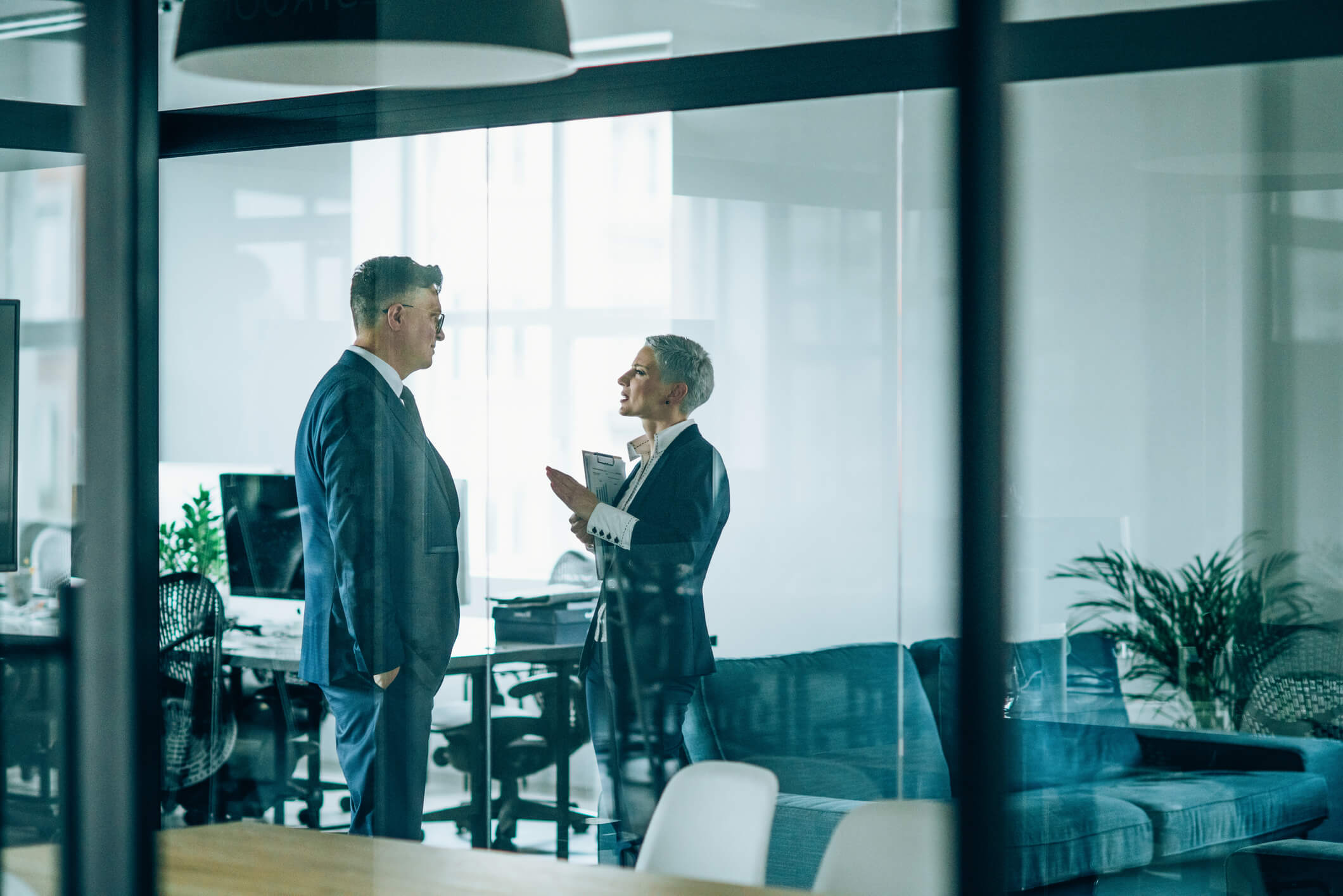 Businesswoman and businessman discussing a deal behind a pane of glass