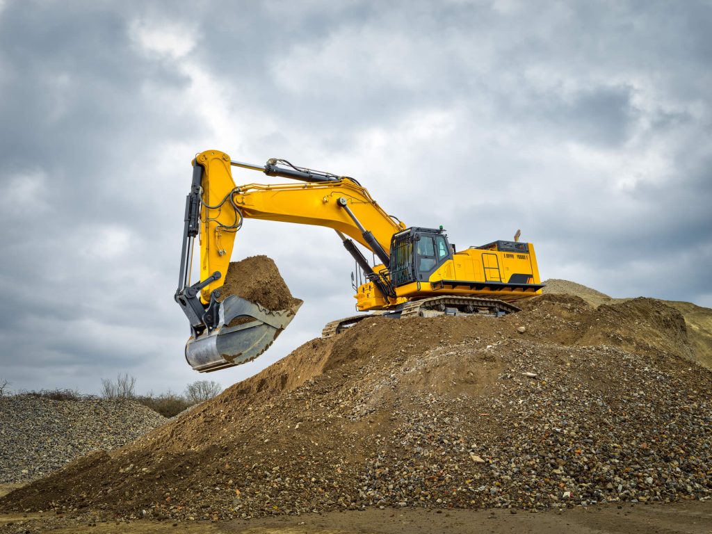 Safety-yellow Excavator on top of a hill of dirt