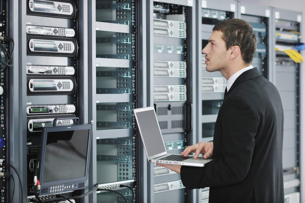 Man holding computer, observing a big data machine. 