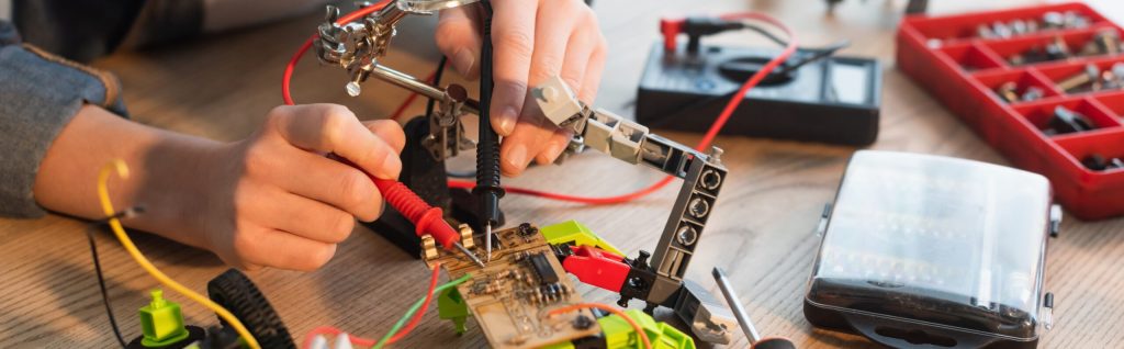 Man working on a circuit board with electric parts attached