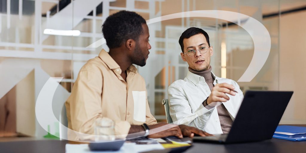 2 men in deep discussion looking at a laptop in an office setting