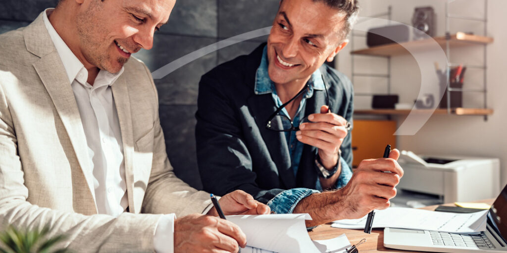 two brokers chatting as they review paperwork